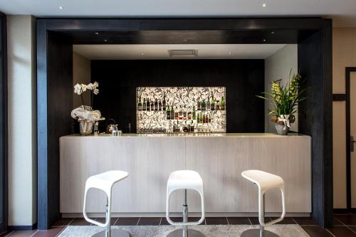 a bar with three white stools in front of it at Hotel Mirage in Florence