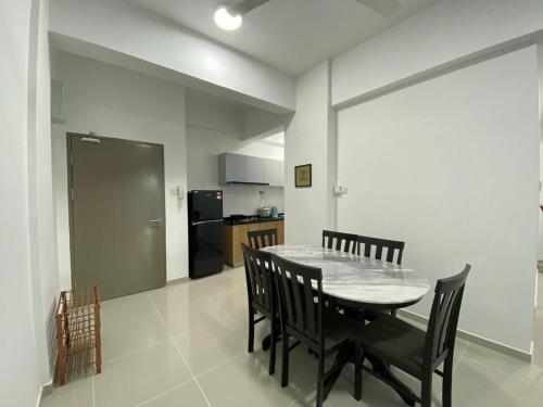 a dining room with a table and chairs and a kitchen at Homestay Sandakan CLL in Sandakan