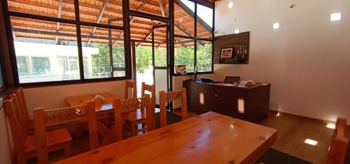 Kurinji Inn في Attigundi: غرفة طعام مع طاولة وكراسي ونوافذ