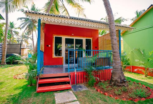 a small red and blue house with a porch at orange sky beach bungalow in Agonda