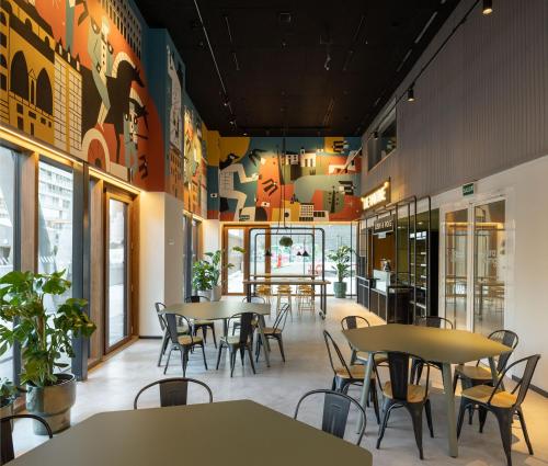 un restaurante con mesas y sillas en una cafetería en Kora Green City - Aparthotel Passivhaus, en Vitoria-Gasteiz