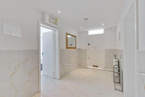 um quarto branco com paredes de mármore branco e um corredor branco em Hamilton Apartments hosted by Maysa London em Londres