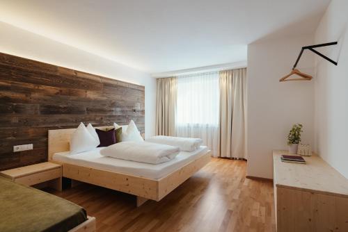 a bedroom with a bed and a wooden wall at La Residence in Molini di Tures