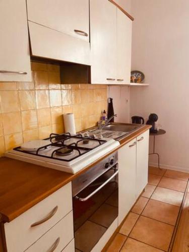 une cuisine avec des armoires blanches et un four à plaques de cuisson dans l'établissement Coquet studio coeur de ville au calme, à Millau