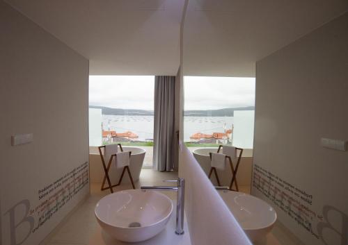 a bathroom with two sinks and a large window at Otantus Hotel in Muros