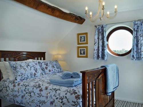 a bedroom with a bed with a blue comforter and a window at The Beehive in Betley