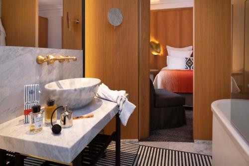 ein Bad mit einem Waschbecken und ein Zimmer mit einem Bett in der Unterkunft Hôtel Vernet Champs Elysées Paris in Paris