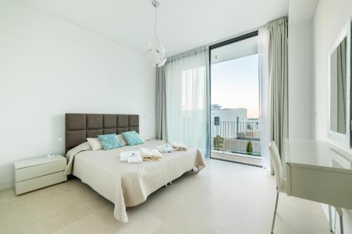 a white bedroom with a bed and a large window at Akamas Turtle Beach №2 in Neo Chorio