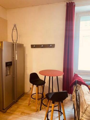 Cette chambre dispose d'une table, de deux chaises et d'un réfrigérateur. dans l'établissement Appartement Centre ville, à Millau