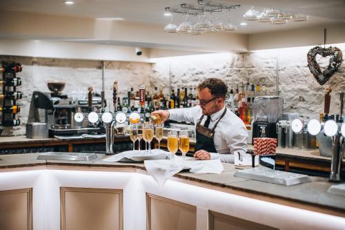 Un uomo che prepara un drink al bar di The Hope & Anchor Restaurant & Rooms a Ross on Wye