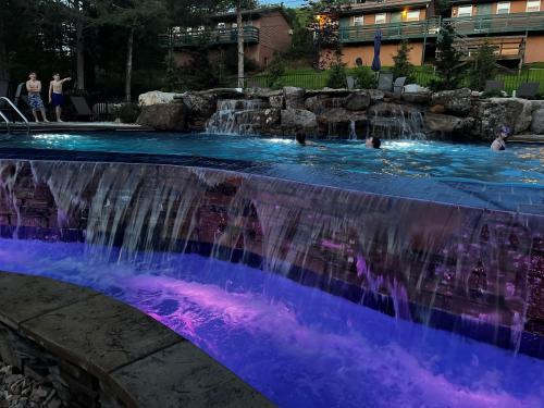 a pool with a waterfall and people in the water at The Bavarian Village Resort in Branson