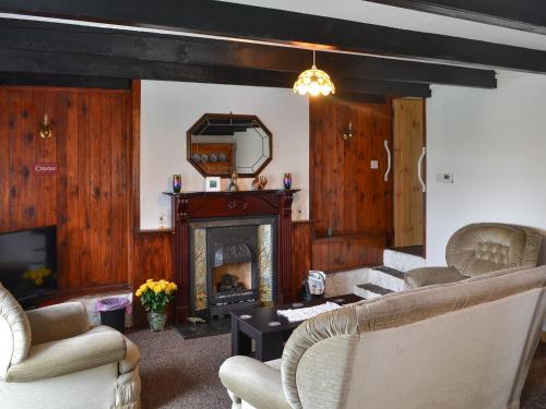 sala de estar con chimenea, sillas y espejo en Ty Newydd Green Cottage, en Llanfachraeth