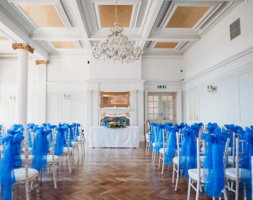 a room with a table with blue chairs and a chandelier at The Queens Hotel in Portsmouth