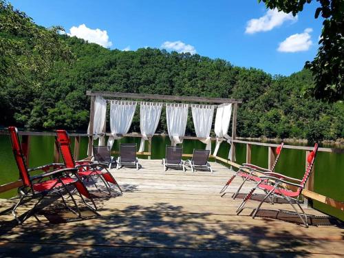 Bălana的住宿－Casa de pe Lac，一组椅子,坐在水边的甲板上