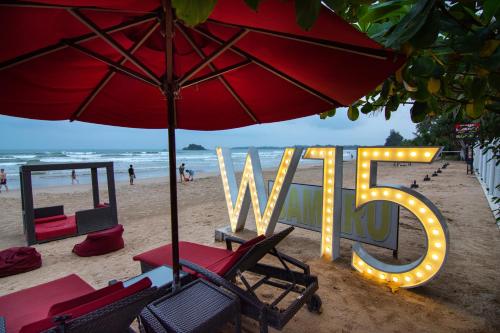 a large sign on the beach with chairs and an umbrella at W15 Weligama in Weligama