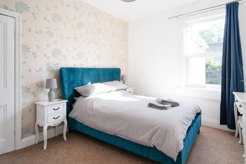 a bedroom with a blue bed and a desk and window at Central Bath apartment in Bath