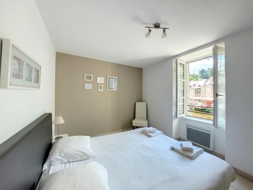 a bedroom with a white bed and a window at Au Fil De L'eau - Les Remparts in Dinan