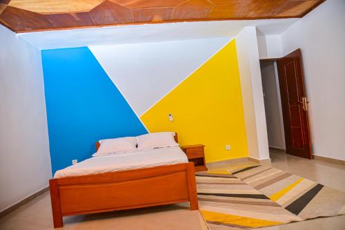 a bedroom with a bed and a colorful wall at Appartement meublé 2 chambres avec salle de bain - 1 salon - 1e cuisine - La Concorde - Quartier Nkomkana in Yaoundé