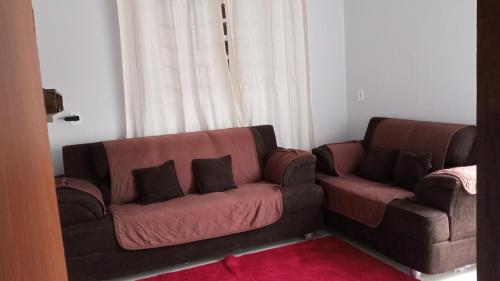 una sala de estar con 2 sofás marrones y una alfombra roja en Casa da Vila de São Jorge en Alto Paraíso de Goiás