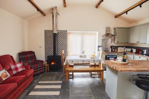 a kitchen and living room with a table and a stove at The Old Dairy - Boutique Countryside Cottage at Harrys Cottages in Pen y Clawdd