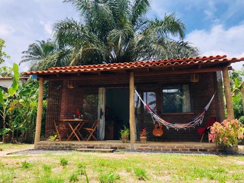 una pequeña casa con una hamaca delante en Aruanã - Praia do Sargi en Serra Grande