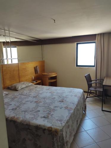 1 dormitorio con 1 cama, 1 silla y 1 mesa en Flat Suite Natal, en Natal