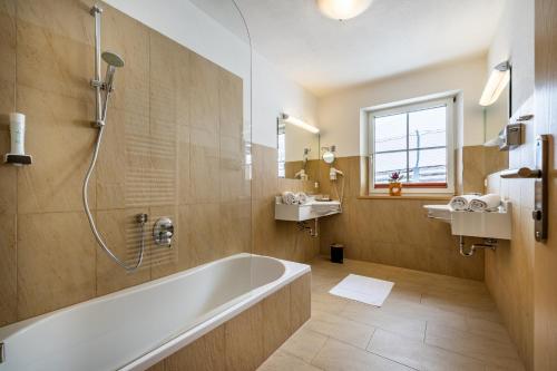 a bathroom with a tub and a shower and a sink at Hotel Breitlehenalm in Obertauern