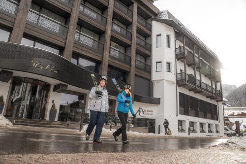 two women walking down a street in front of a building at Stella Hotel - My Dolomites Experience in Selva di Val Gardena