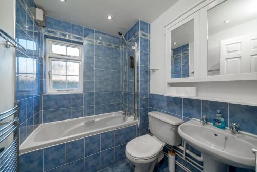 a blue tiled bathroom with a toilet and a sink at Crawley 1-Bedroom Pet Friendly Apartment in Three Bridges