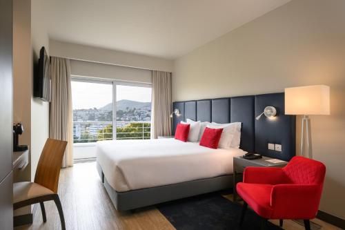 een hotelkamer met een groot bed en een rode stoel bij Melia Setubal in Setúbal