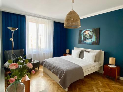 a bedroom with blue walls and a bed and a vase of flowers at Smile Apartments Center Kraków Old Town in Kraków