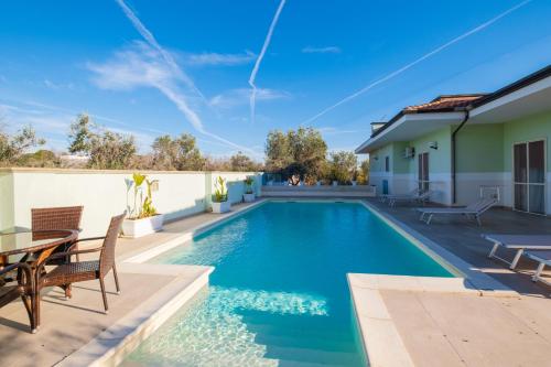 a swimming pool with a table and chairs next to a house at Villa Vimade con Piscina Privata in Marina di Mancaversa