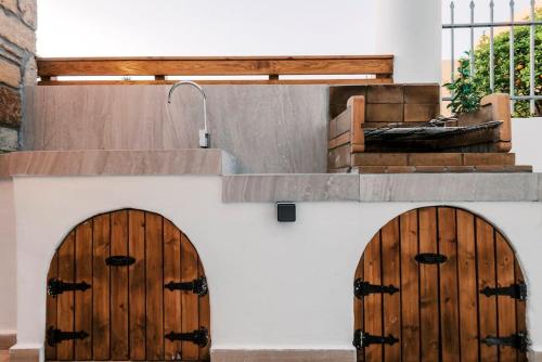 zwei Holztüren an der Seite eines Gebäudes in der Unterkunft Myrovolos luxury Angie's house in Ialyssos