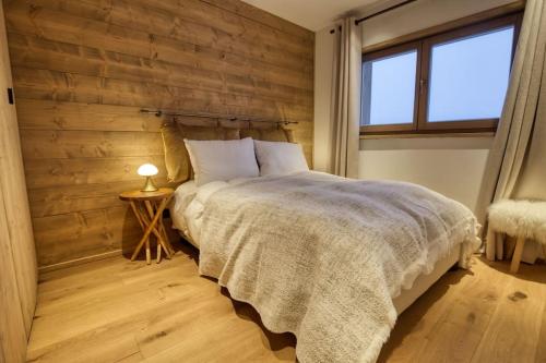 um quarto com uma cama e uma parede de madeira em Magnifique appartement dans luxueux chalet - ARAVIS em Crest-Voland