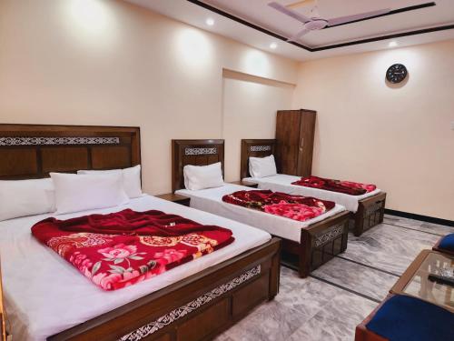 - une chambre avec 2 lits et des draps rouges dans l'établissement New Palace Guest House, à Islamabad