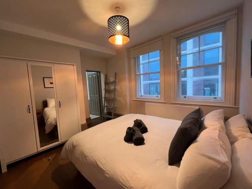 un grand lit blanc avec un chien noir posé sur lui dans l'établissement Modern flat near Oxford Street, à Londres