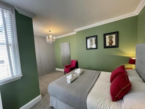 1 dormitorio con paredes verdes y 1 cama con almohadas rojas en Regency Apartment - Marine Square By Crown Gardens Holiday Homes, en Brighton & Hove