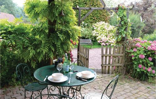 une table et des chaises vertes dans un jardin dans l'établissement Gites Des Blanchiries, à Aubin-Saint-Vaast
