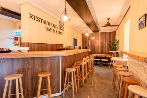 un bar dans un restaurant avec tabourets en bois dans l'établissement Apartamentos Day Madrid BALLESTA Centro Gran Via Sol Malasaña, à Madrid