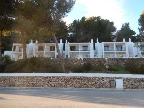a large white building with a white fence at Alta Galdana Playa in Cala Galdana