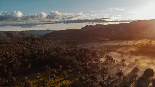 a view of a valley with trees and the sun setting at Vila Toá in Alto Paraíso de Goiás