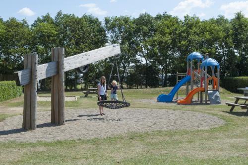 a woman and a child playing in a playground at Møgeltønder Camping & Cottages in Møgeltønder