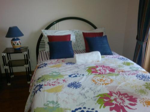 Cama con edredón y almohadas coloridos en Aguda Beachfront Apartment en Aguda