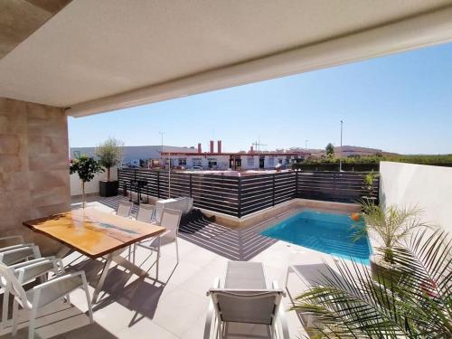 a patio with a table and chairs and a swimming pool at Exclusive modern Villa with private pool in Los Montesinos