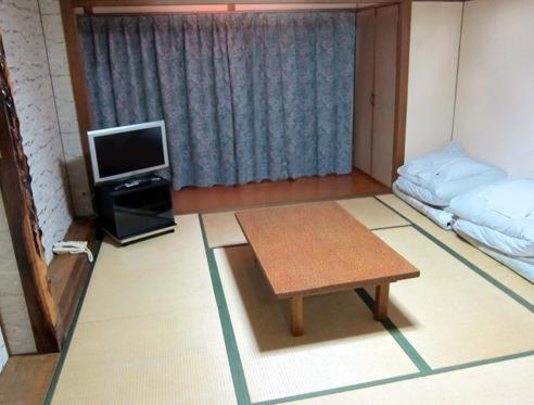a room with a table and a tv and a bed at Rinkai Hotel Kitamise in Sakai