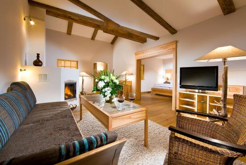 een woonkamer met een bank, een tv en een open haard bij Berghotel Rehlegg in Ramsau