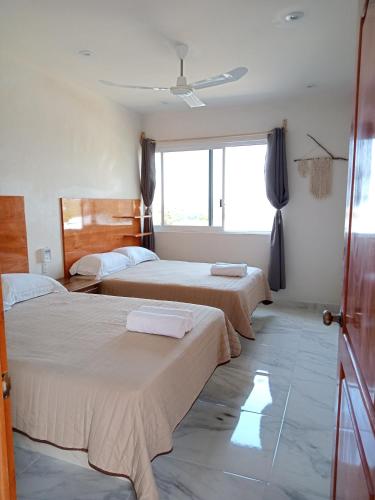 a bedroom with two beds and a window at Villas victoria mirador in Zihuatanejo
