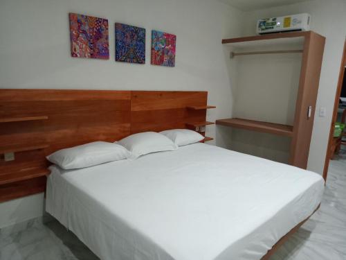 a bedroom with a white bed with a wooden headboard at Villas victoria mirador in Zihuatanejo