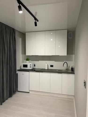 a kitchen with white cabinets and a microwave at пр. Металургів 19 in Kryvyi Rih