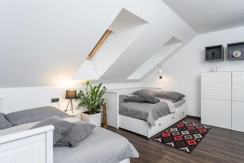 two beds in a white bedroom with a attic at ESCAPE THE ORDINARY (Sauna & Jacuzzi) in Jesenice